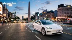Un Tesla Model 3 blanco circula por una avenida de Buenos Aires al atardecer con el Obelisco de fondo, envuelto por una red digital luminosa de nodos y lineas que representa la conduccion conectada y la inteligencia artificial